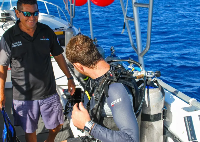 Plongeur s'équipant sur un bateau avec l'aide d'un membre d'équipage