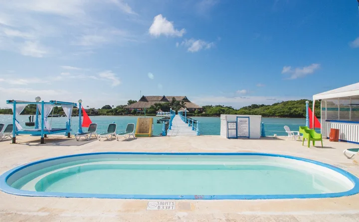 Terrasse avec piscine, ponton en bois et végétation tropicale au loin