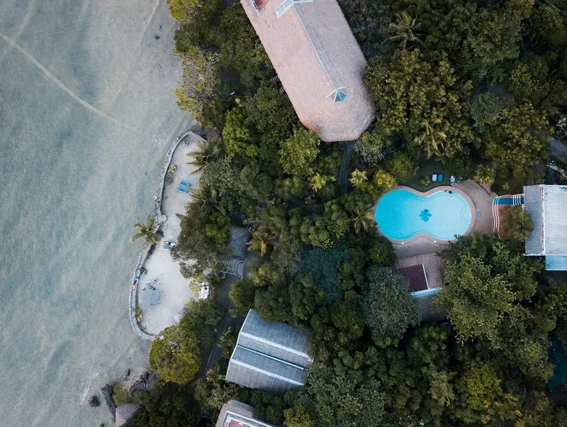 Vue aérienne d'un complexe hôtelier avec piscine et végétation tropicale