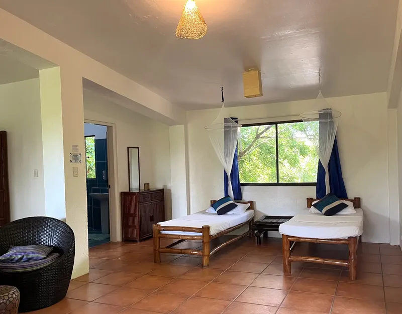 Chambre avec deux lits simples, moustiquaires et vue sur végétation