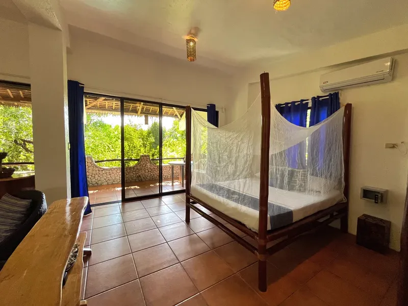 Chambre avec lit à baldaquin, vue sur la végétation tropicale, intérieur