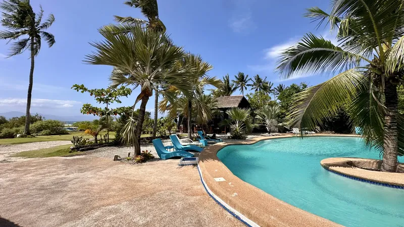 Piscine bordée de transats et de végétation tropicale ensoleillée