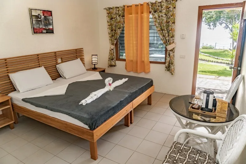 Chambre d'hôtel avec lit décoré, table de chevet et vue sur jardin