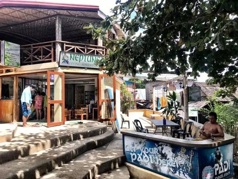 Façade d'un centre de plongée avec des personnes et mobilier extérieur
