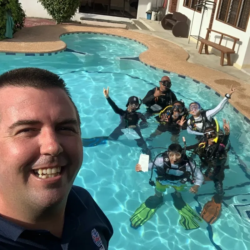 Groupe de plongeurs souriants dans une piscine avec un instructeur
