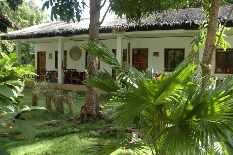 Façade d'un bâtiment blanc avec végétation tropicale luxuriante devant