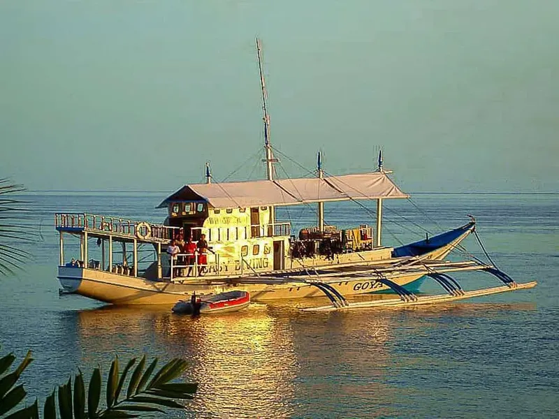 Bateau de plongée avec des passagers sur l'eau calme au coucher du soleil