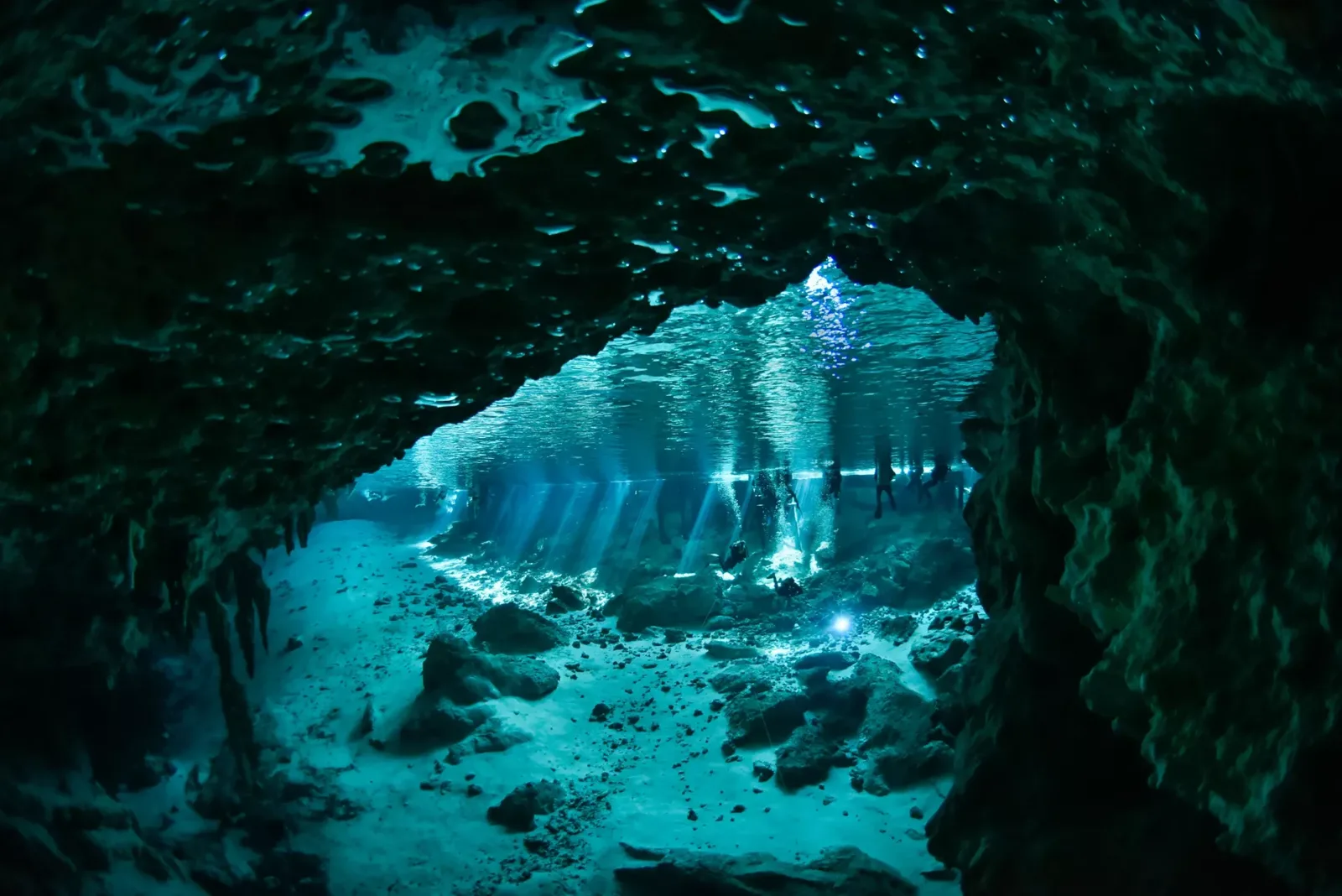 Plongeurs explorant une grotte sous-marine éclairée par des rayons de soleil