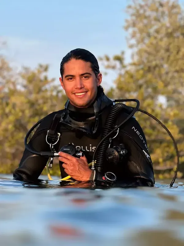 Plongeur souriant en équipement complet, à la surface de l'eau