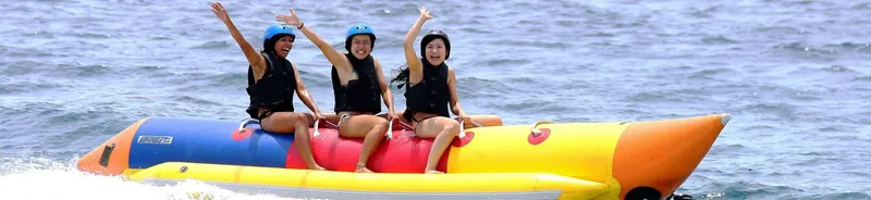 Trois personnes s'amusent sur un bateau banane en mer