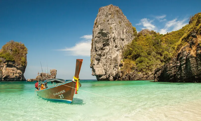 Bateau longtail traditionnel amarré dans une baie turquoise paradisiaque