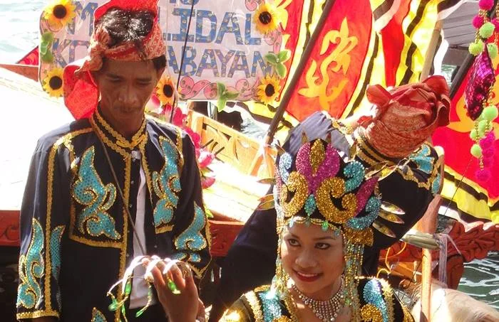 Deux personnes souriantes en costumes traditionnels sur un bateau décoré