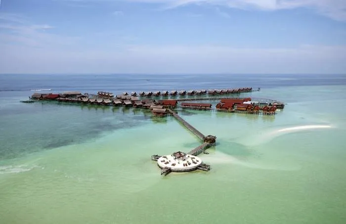 Vue aérienne d'un complexe hôtelier sur pilotis dans une eau turquoise
