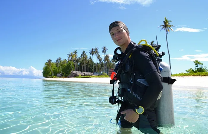 Plongeur en combinaison sortant de l'eau sur une plage tropicale