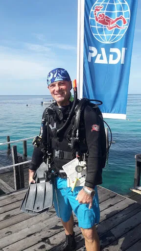 Plongeur souriant sur un ponton avec son équipement complet PADI