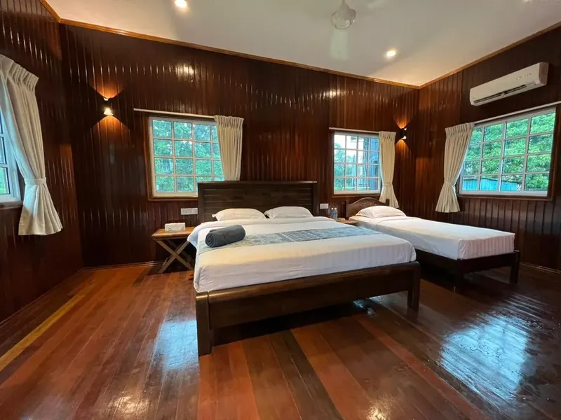 Chambre avec lits, parquet en bois, murs en bois et fenêtres