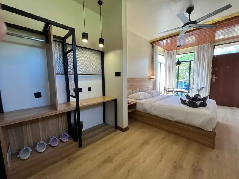 Chambre d'hôtel moderne avec bureau, lit et ventilateur de plafond