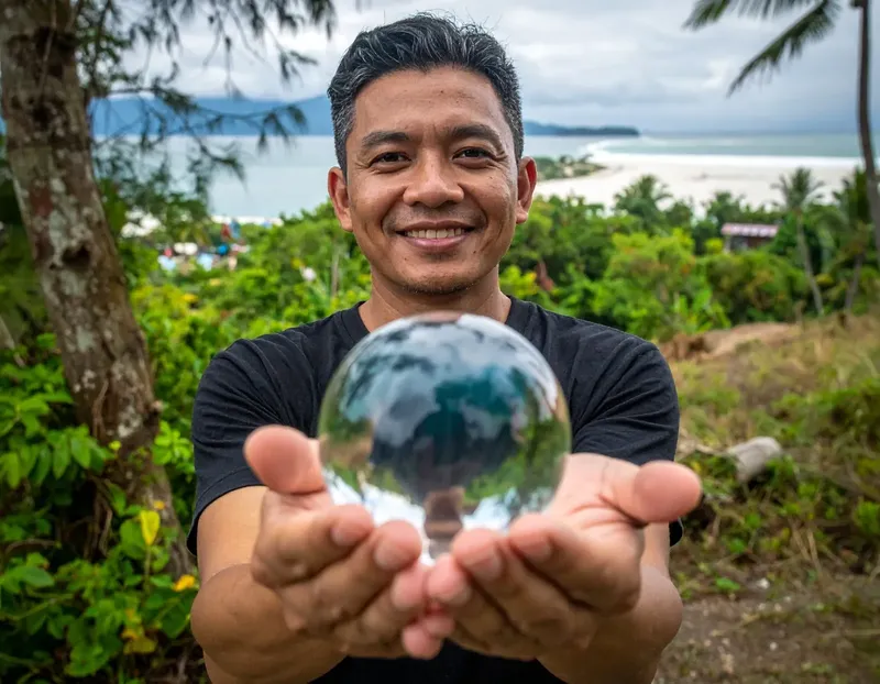 Homme souriant tenant une sphère de verre avec paysage marin