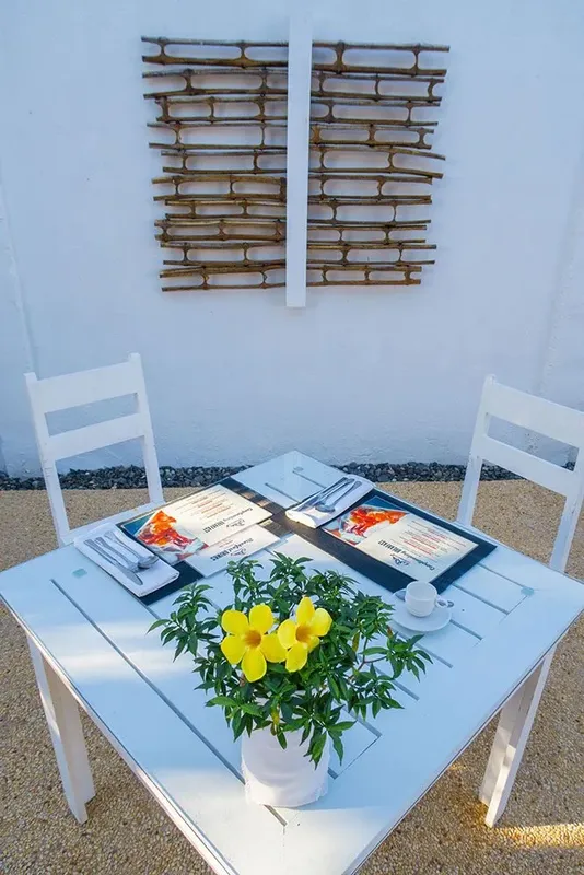 Table blanche avec menus, couverts et plante jaune en pot