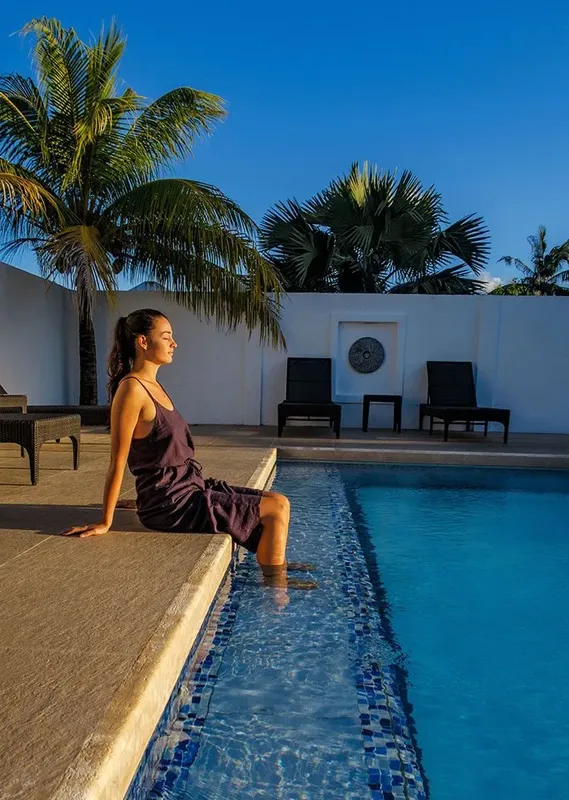 Jeune femme assise au bord d'une piscine ensoleillée relaxante