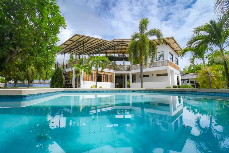 Bâtiment blanc avec piscine au premier plan et végétation tropicale