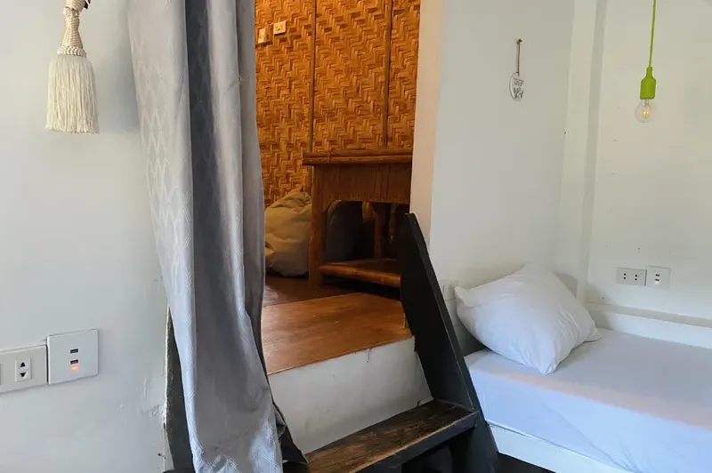 Intérieur d'une pièce avec un lit, un escalier et un mur en bambou