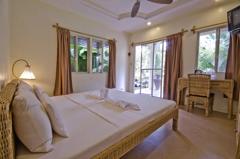 Chambre d'hôtel avec lit double, bureau en rotin et vue sur l'extérieur