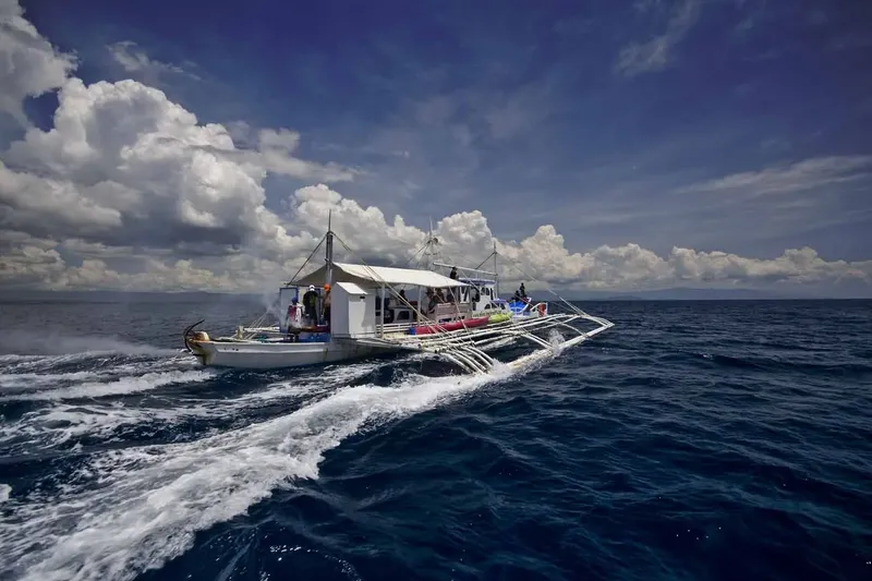 Bateau de plongée filant sur une mer bleue sous un ciel nuageux