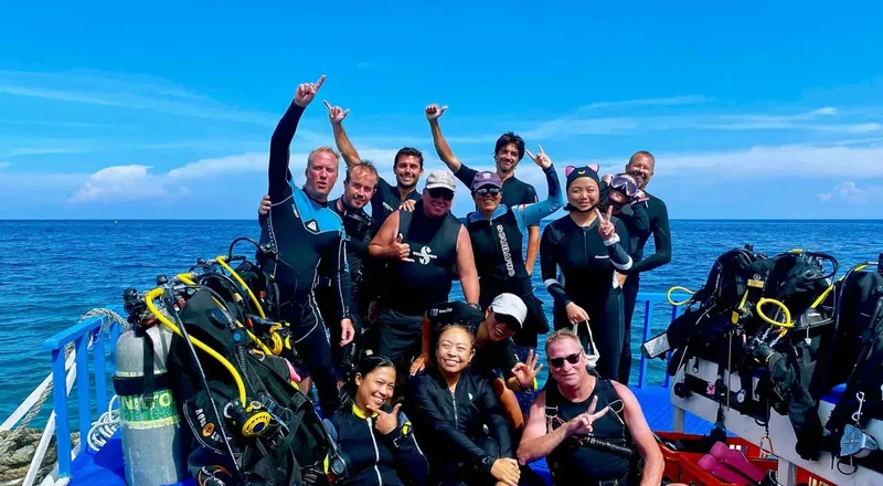 Groupe de plongeurs souriants sur un bateau en mer, équipement visible
