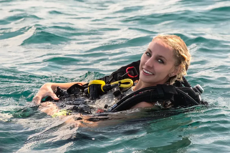 Plongeuse souriante en surface avec son équipement de plongée complet