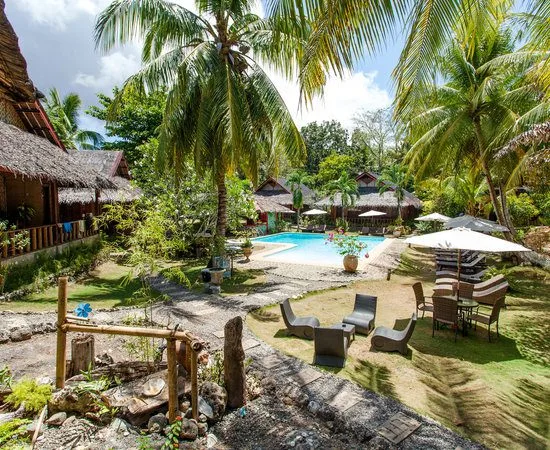 Piscine et bâtiments du centre de plongée entourés de végétation tropicale