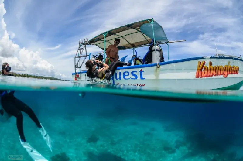 Plongeurs s'équipent sur un bateau de plongée en mer turquoise