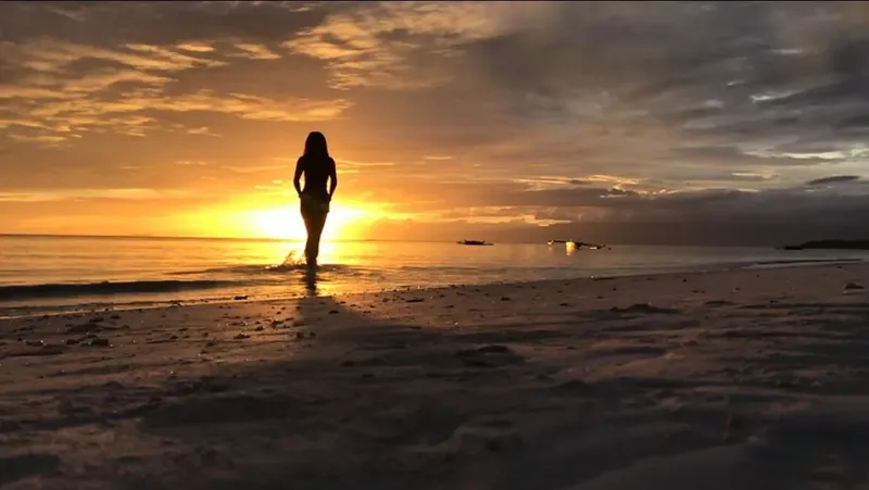 Silhouette d'une personne marchant vers le soleil couchant sur la plage