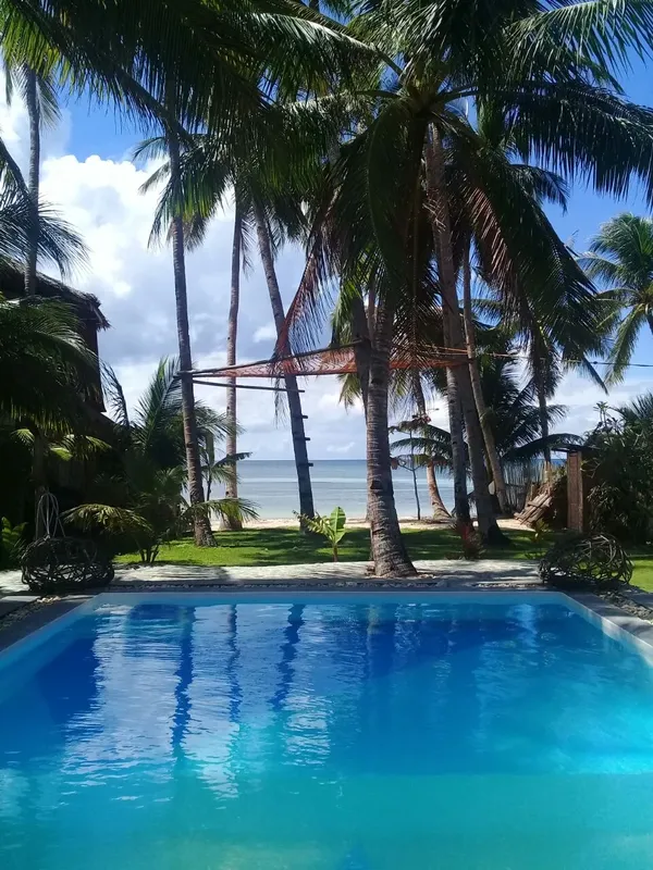 Piscine turquoise bordée de palmiers avec vue sur la mer