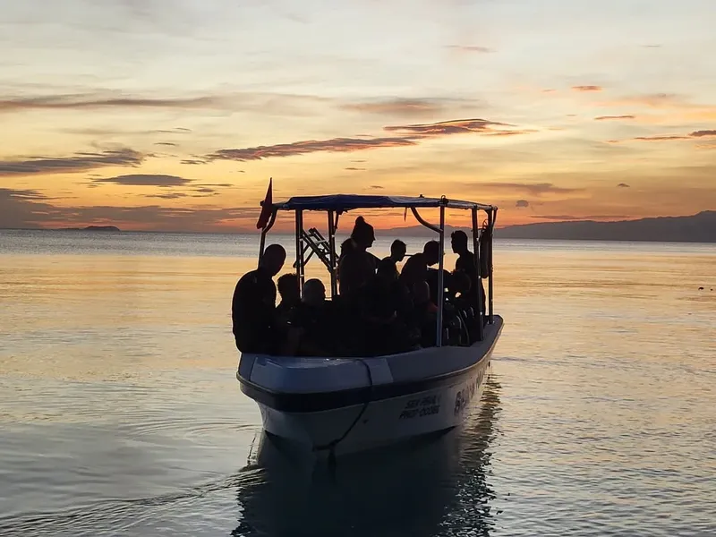 Groupe de personnes à bord d'un bateau au coucher du soleil