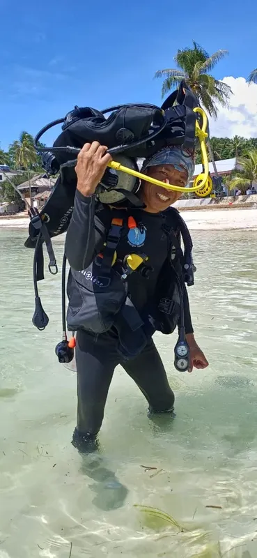 Plongeur sortant de l'eau avec son équipement complet sur la plage