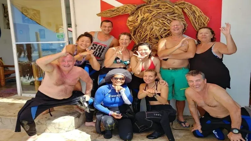 Groupe de plongeurs souriants posant devant un décor de tortue tressée