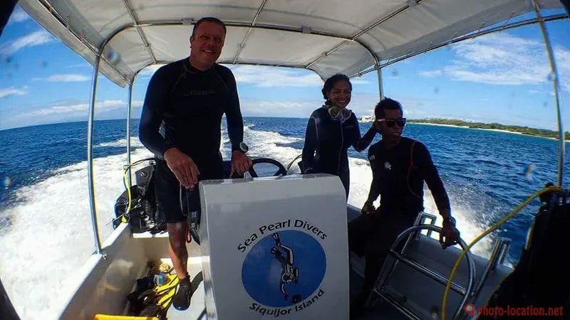 Trois personnes souriantes à bord d'un bateau de plongée en mer