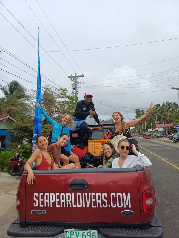 Groupe de personnes souriantes sur le plateau d'un pick-up rouge
