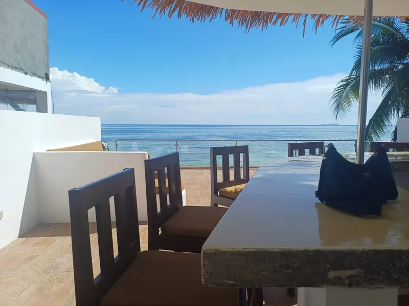 Terrasse avec tables et chaises donnant sur une mer bleue dégagée