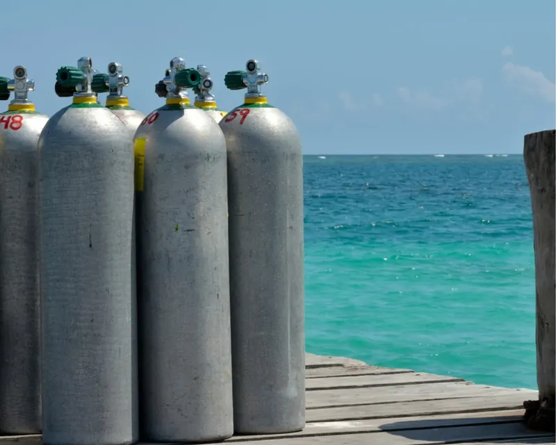 Bouteilles de plongée alignées sur un ponton en bois face à la mer
