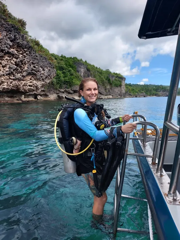 Plongeuse souriante équipée sortant de l'eau sur un bateau