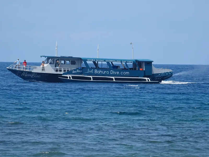 Catamaran bleu en mer avec des passagers et le nom Bahura Dive