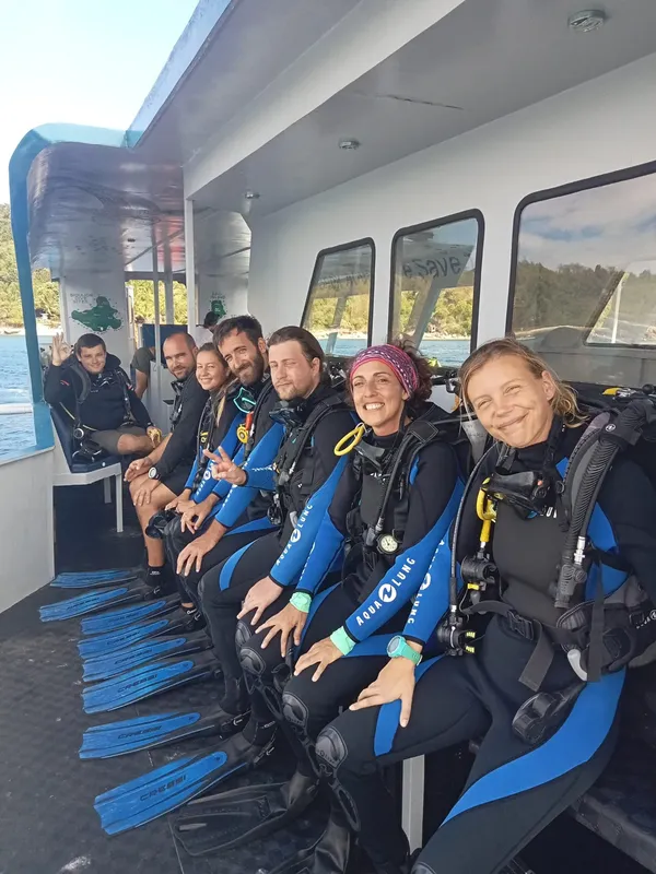 Groupe de plongeurs souriants assis sur les bancs d'un bateau