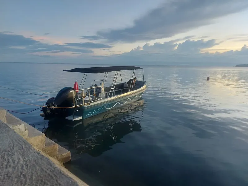 Bateau de plongée amarré au quai avec ciel nuageux et mer calme