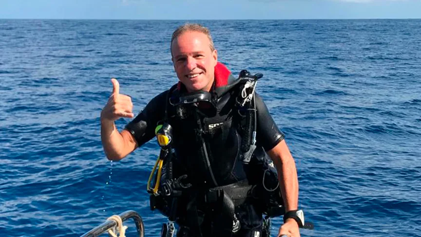 Plongeur souriant avec signe ok, équipé en mer, ciel bleu