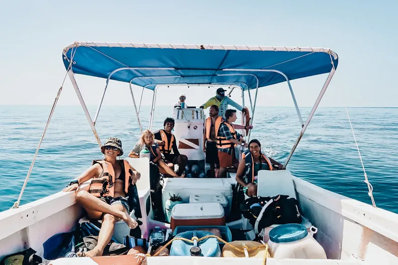 Groupe de plongeurs souriants sur un bateau en mer, équipés