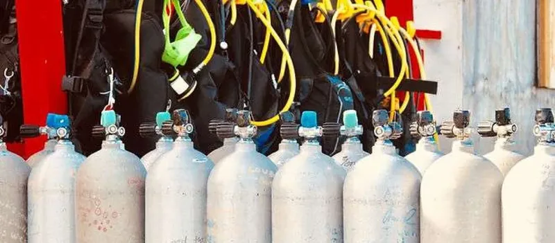 Rangée de bouteilles de plongée avec détendeurs et gilets noirs