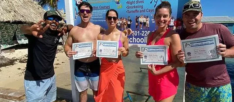 Groupe de plongeurs souriants tenant leurs certificats de plongée en extérieur