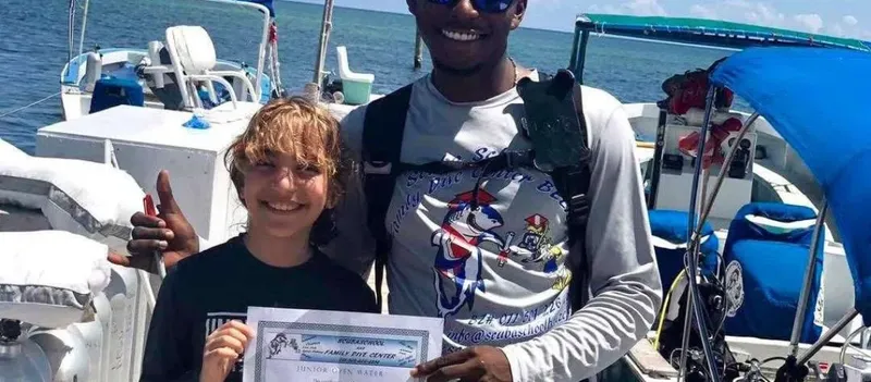 Deux personnes souriantes posent avec un certificat de plongée sur un bateau